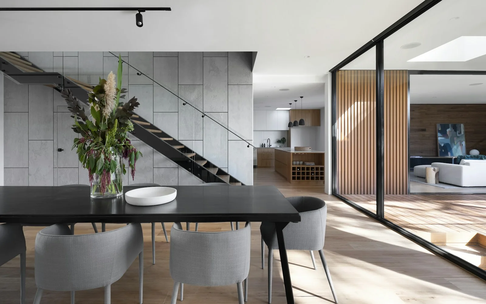 A finished modern interior with a sculptural staircase and dining table