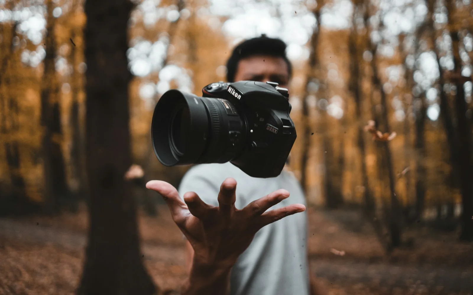 A photographer holding a camera outdoors in autumn light
