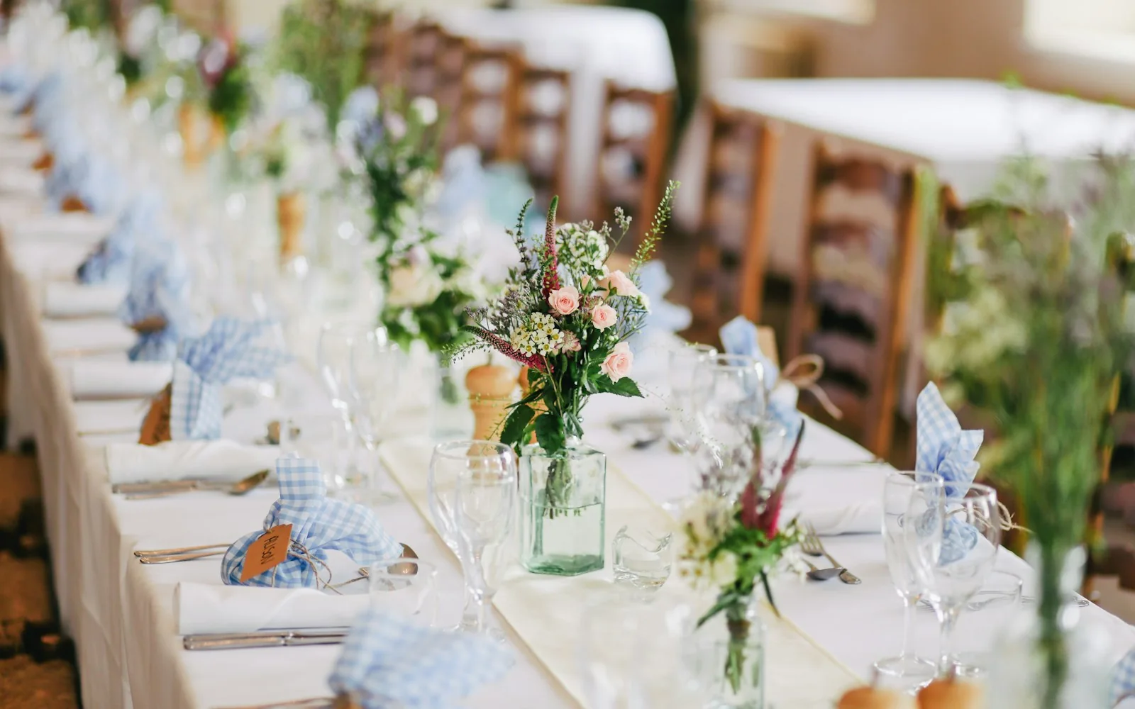 An elegant wedding table with flowers, glassware and warm wood chairs